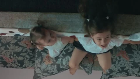 Two cute sisters playing on sofa and talking. Having fun time at home. Stock Footage 251730463