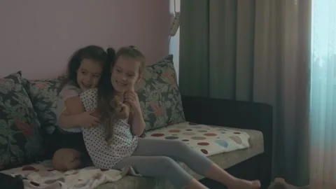 Two cute sisters playing on sofa. Schoolgirl and preschool sister are having fun Stock Footage 251731692