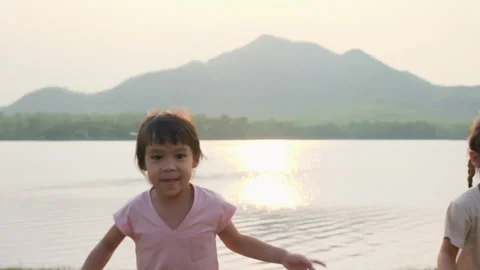Two cute sisters running together by the lake at sunset. Stock Footage 172540095