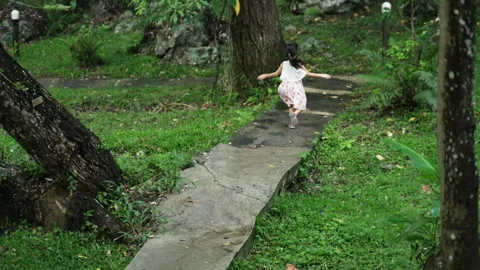 Two cute sisters running together on a stone path in a botanical garden. Stock Footage 241979994