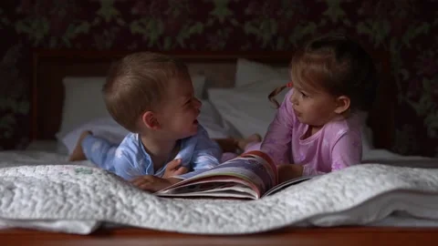 Two cute smiling preshool, toddler children on pajamas read book of fairy tales Video stock 158898432
