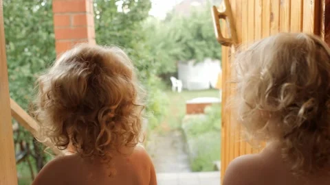 Two cute twins kids looking to rainy cloudy weather at village house backyard Stock Footage 201954830