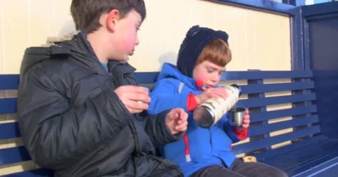 Two cute young boys sitting on a bench and drinking tea Stock Footage 60781350