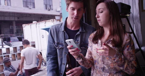 Two cute young happy hipster friends standing in doorway talking and drinking at Video stock 57989985