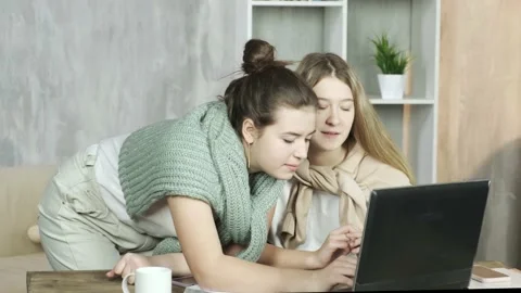 Two cute young students looking at a laptop, laughing and having fun, chattin Stock Footage 149218417