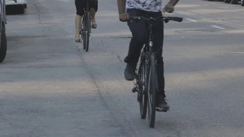 Two cyclist pedal down urban street Stock Footage 70610165