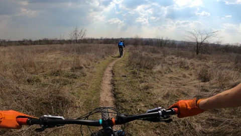 Two cyclists are riding the trail across the field. From the first person. Stock Footage 151542009