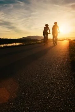 Two cyclists are on sunset road Stock Photos