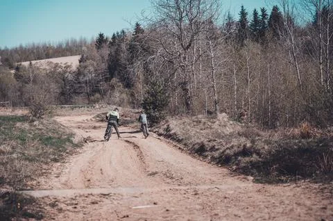 Two cyclists on a dirt path, enjoying a sunny day outdoors. Trees and a for.. Fotos Stock