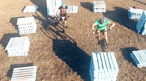 Two cyclists doing jump MTB tricks bicycle HD aerial video. Mountain bike trial Stock Footage 67861626