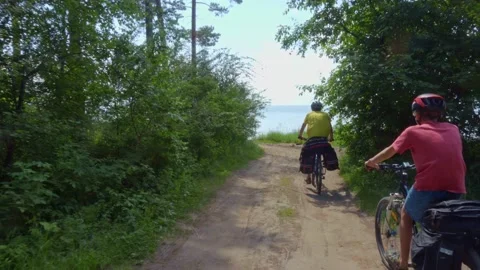 Two cyclists drive out of the forest to the seashore. Video stock 158716937
