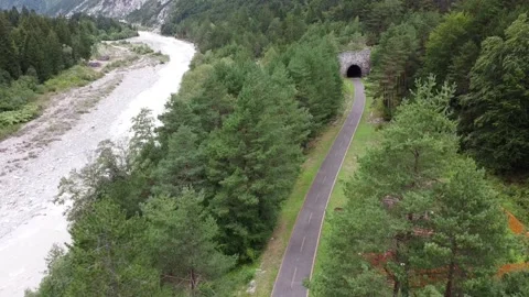 Two cyclists heading towards a tunnel on Alpe Adria cycling route Stock Footage 140897762