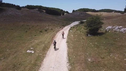 Two Cyclists at morning, ride on a path in an open mountain valley, aerial vi Stock Footage 113041359