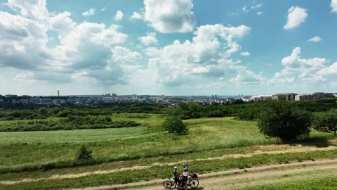 Two cyclists pause on a rural dirt road overlooking a city skyline under Stock Footage 336569042