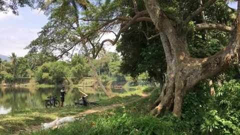 Two Cyclists Relaxing Beside a Lake in Garut, West Java, Indonesia Видео 343560985