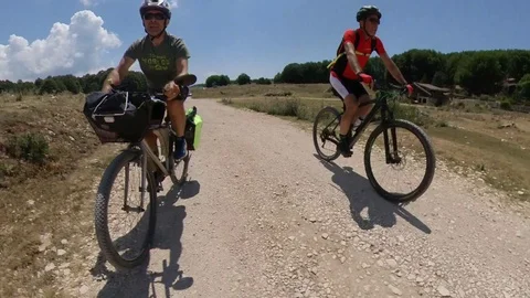 Two Cyclists ride on a mountain path at sunny morning, VR360 effect Stock Footage 113054522