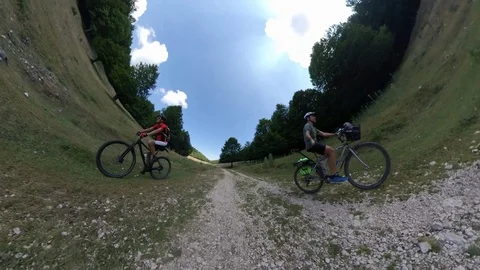 Two Cyclists ride on a mountain path at sunny morning, VR360 effect Stock Footage 113055164