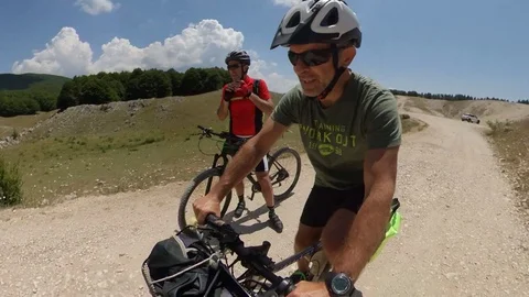 Two Cyclists ride on a mountain path at sunny morning, VR360 effect Stock Footage 113055872