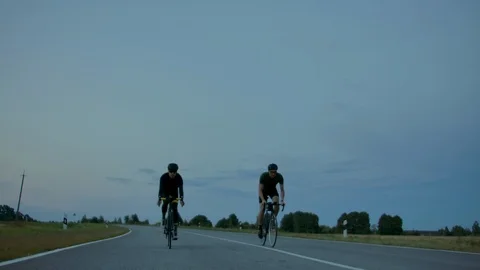 Two cyclists ride on the road in the evening after sunset. Early morning Stock Footage 115479676