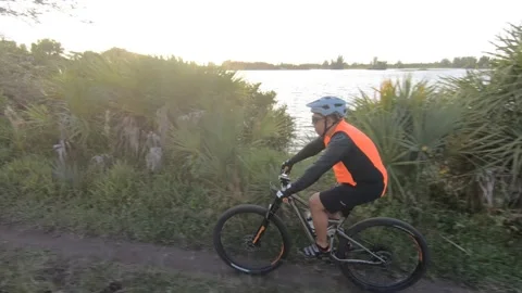 Two Cyclists Riding Along Lake at Sunset Stock Footage 200897998