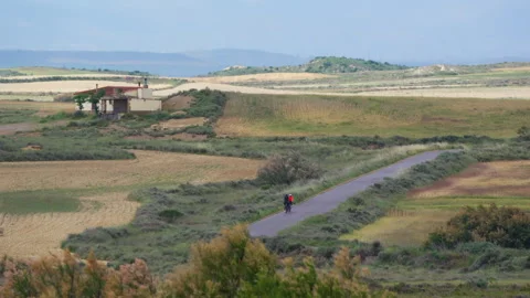 Two cyclists riding rural road through countryside fields Video stock 337797149