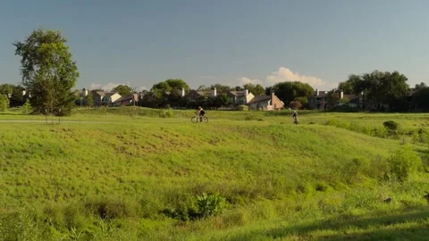 Two cyclists rounding a bend and up a slight climb under blue skies in Stock Footage 342283847