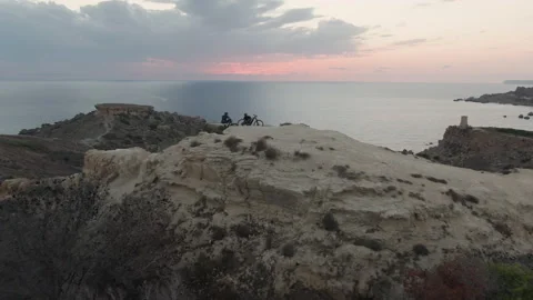 Two Cyclists Sitting on a Hill Admiring the View of the Sea Drone Shot Vidéo 139709474