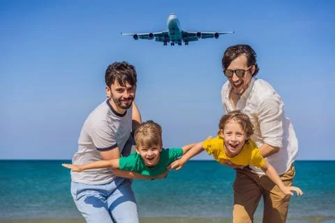 Two dads and two sons have fun on the beach watching the landing planes Stock Photos
