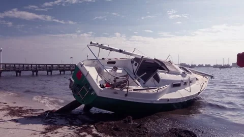 Two Damaged Sailboat leaning on the after a storm in Gulfport, Florida. Looking  Stock Footage 260993313
