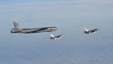 Two Danish Air Force F-16 aircraft flying with U.S. Air Force B-52 above clouds Stock Footage 292778216
