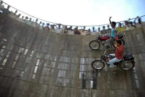 Two dare devil performers performing on motorbikes in well of death at ann... Stock Photos