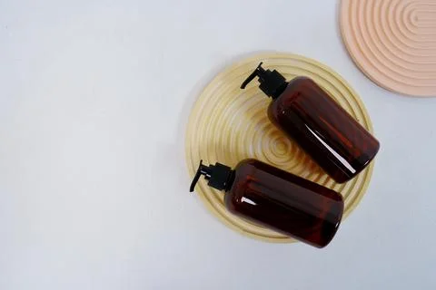 Two dark bottles for shampoo or cosmetics on a light background and round Stock Photos