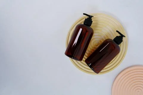 Two dark bottles for shampoo or cosmetics on a light background and round Stock Photos