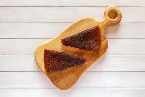 Two dark brown triangular fruit pastille pieces placed on light wooden cutt.. Stock Photos