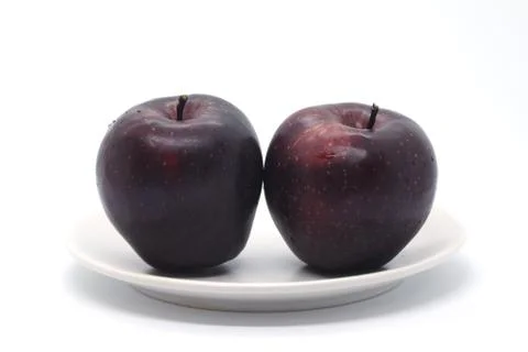 Two dark red apples on a light plate isolated on a white background Stock Photos