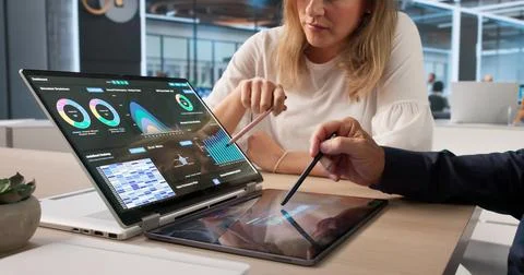 Two Data Analysts Discussing Financial KPIs Together Using Laptops. Stock Photos