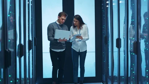 Two data center IT technicians walking along server cabinet and providing Видео 125278395