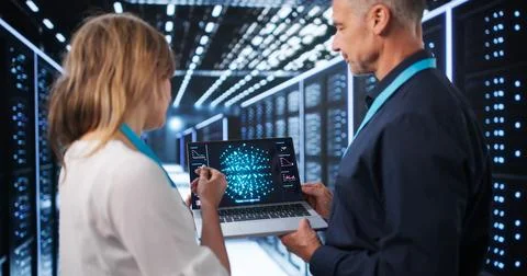 Two Data Scientists Use Laptops Discussing AI Model Development In Tech Cente Stock Photos