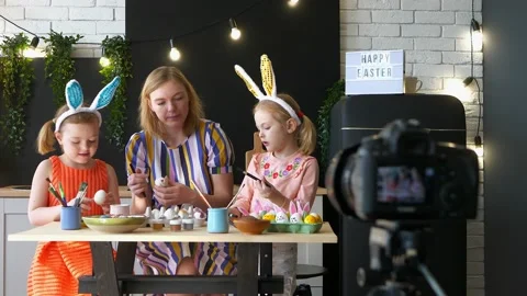 Two daughters and mom are coloring Easter eggs and recording video on camera. Stock Footage 169971564