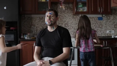 Two Daughters Draw at the Daddy on the Face, in the Kitchen Stock Footage 74697758