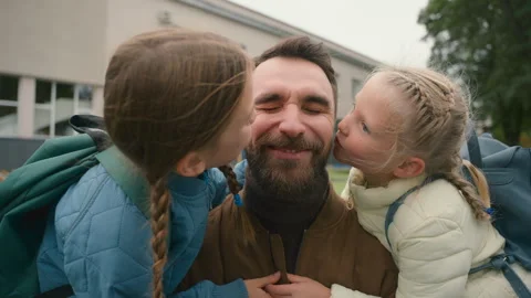 Two daughters kiss father dad on cheek h... | Stock Video | Pond5