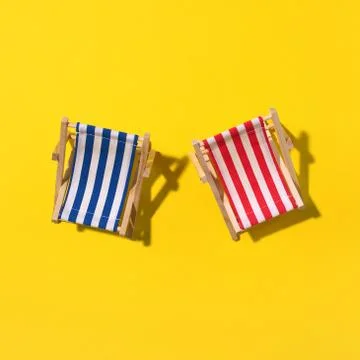 Two deck chairs with hard shadow, monstera and palm leaves on yellow paper Stock Photos