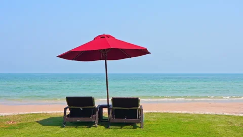 Two Deck chairs Under Parasol on green grass part of the beach lounge Stock Footage 148309628