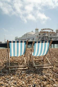Two deckchairs on Brighton beach with a view of Brighton Palace Pier Stock Photos