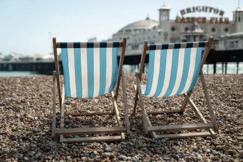 Two deckchairs on Brighton beach with a view of Brighton Palace Pier Stock Photos