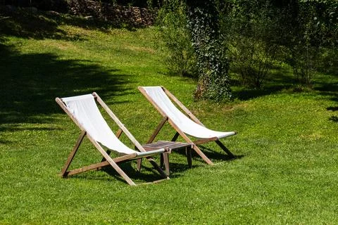 Two deckchairs on a green lawn Stock Photos