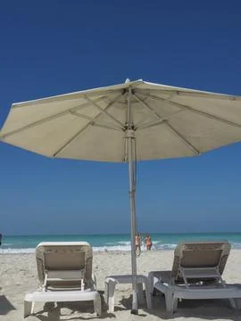Two deckchairs under a large parasol on the beach overlooking the sea, Stock Photos