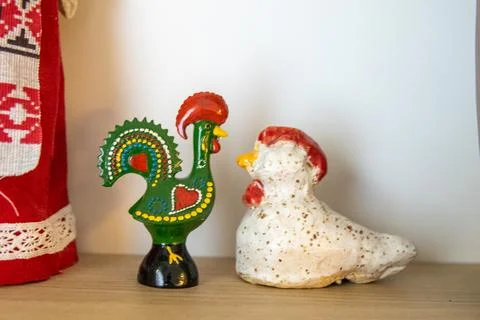 Two decorative ceramic rooster and hen figurines placed on a wooden surface.. Stock Photos