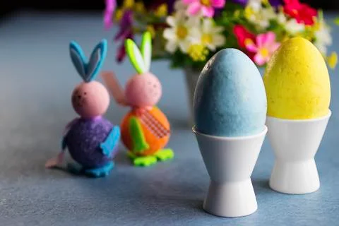 Two decorative eggs in white coasters, two decorative bunnies and bright flow Foto stock