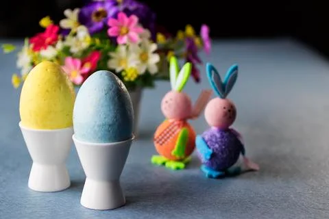 Two decorative eggs in white coasters, two decorative bunnies and bright flow Foto stock